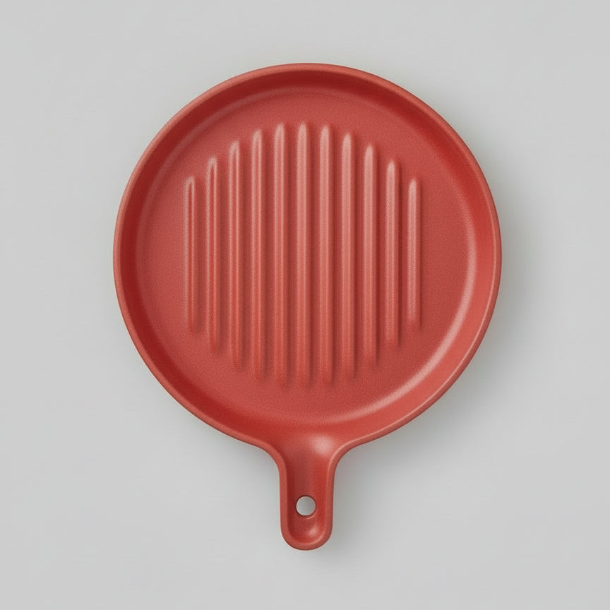 A red ceramic round grill plate with visible ridges, displayed on a two-tone background.