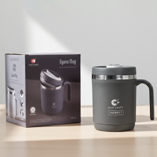 Black insulated mug with handle next to its packaging on a light surface.